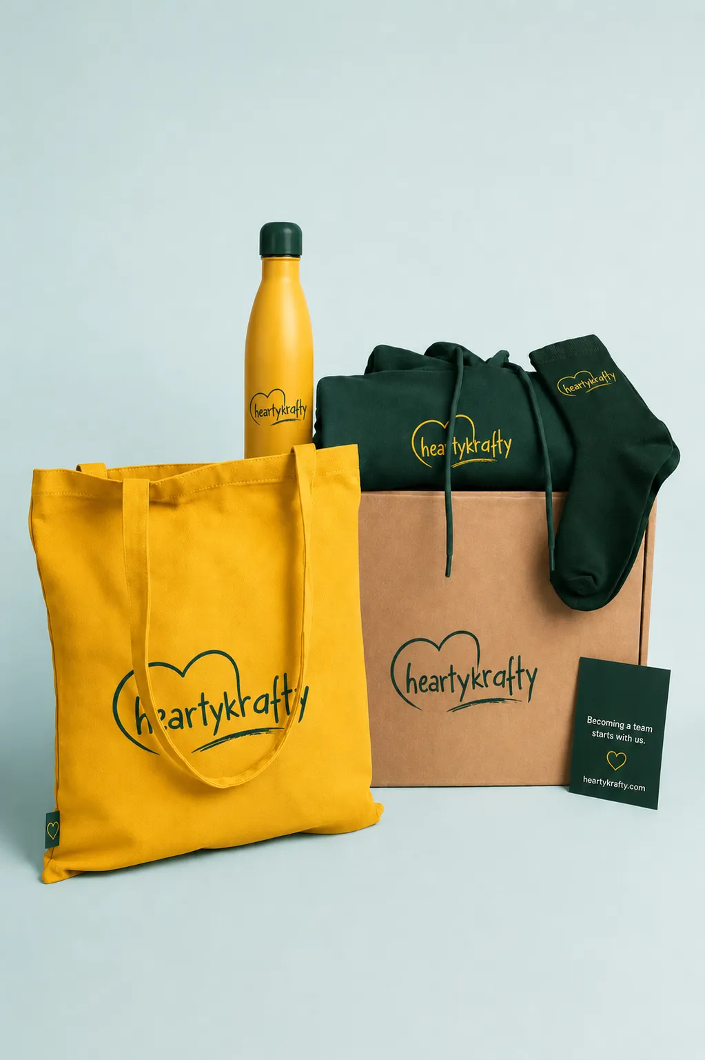 A HeartyKrafty branded tote bag, water bottle and socks arranged as a gift set