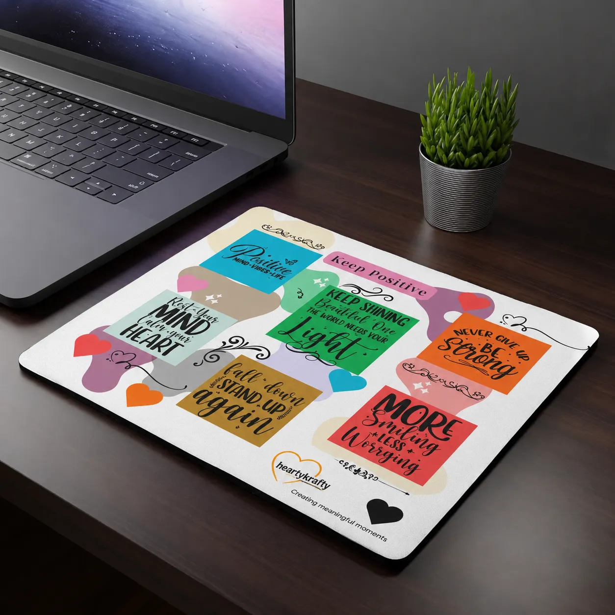 A branded mouse pad on a desk beside a laptop